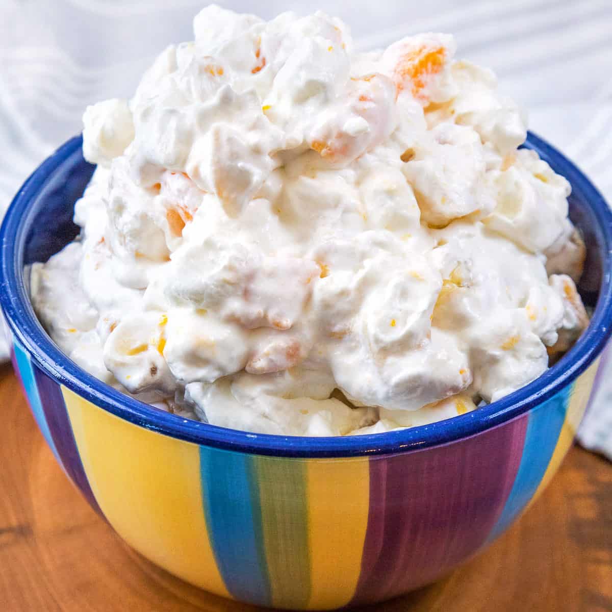 Fruit salad with cool whip recipe in a colorful bowl close up.